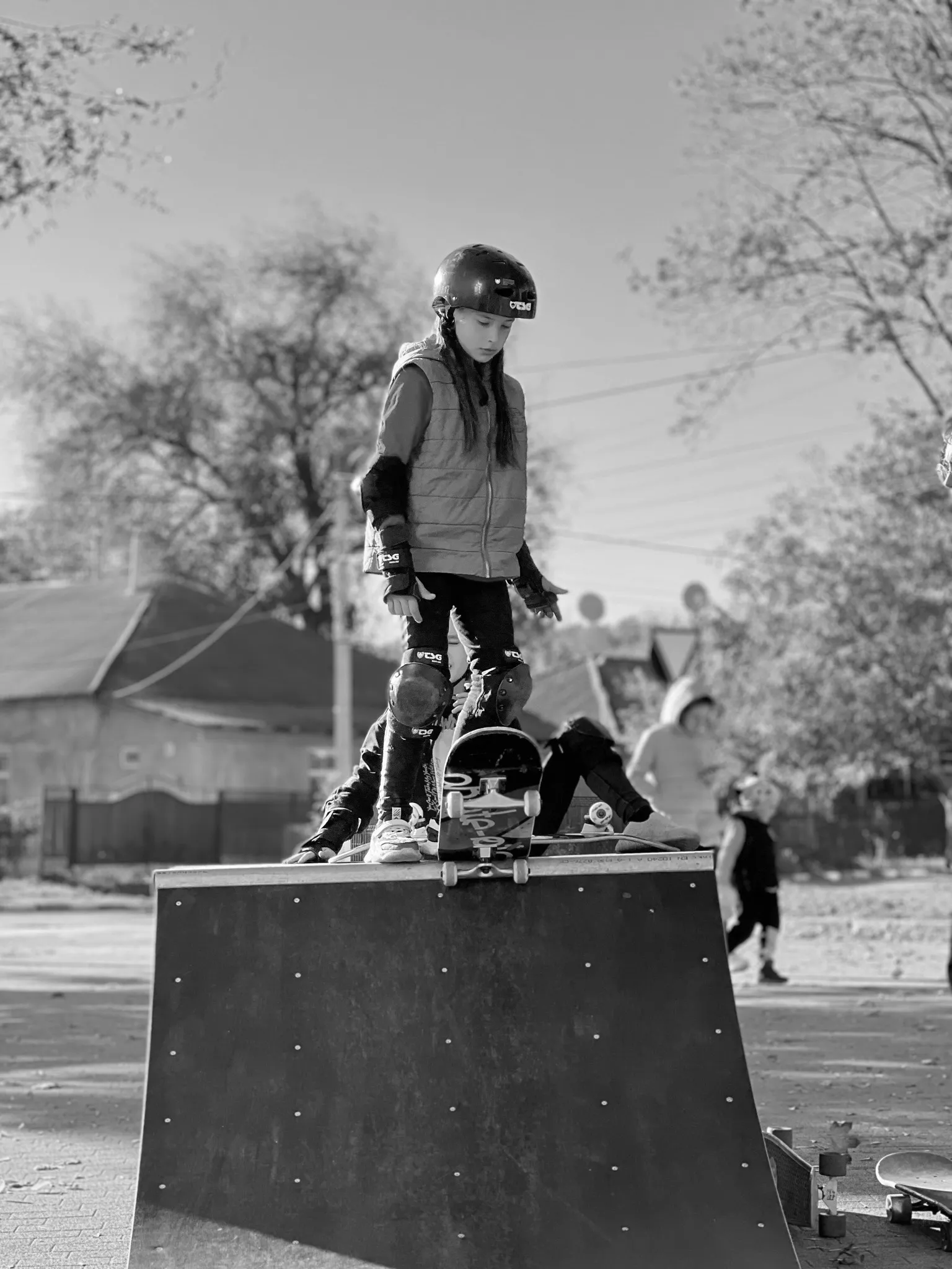 A young girl standing on a skateboard at the top of a ramp